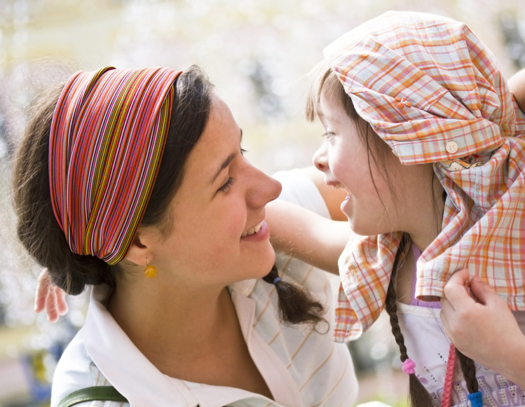 Donna e bambina disabile si guardano sorridenti